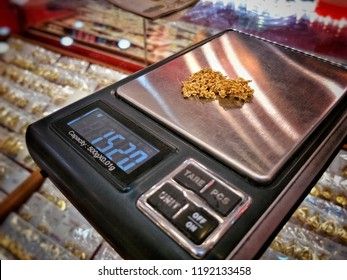 En guldhalskedja vägs på en digital precisionsvåg i en smyckesbutik.